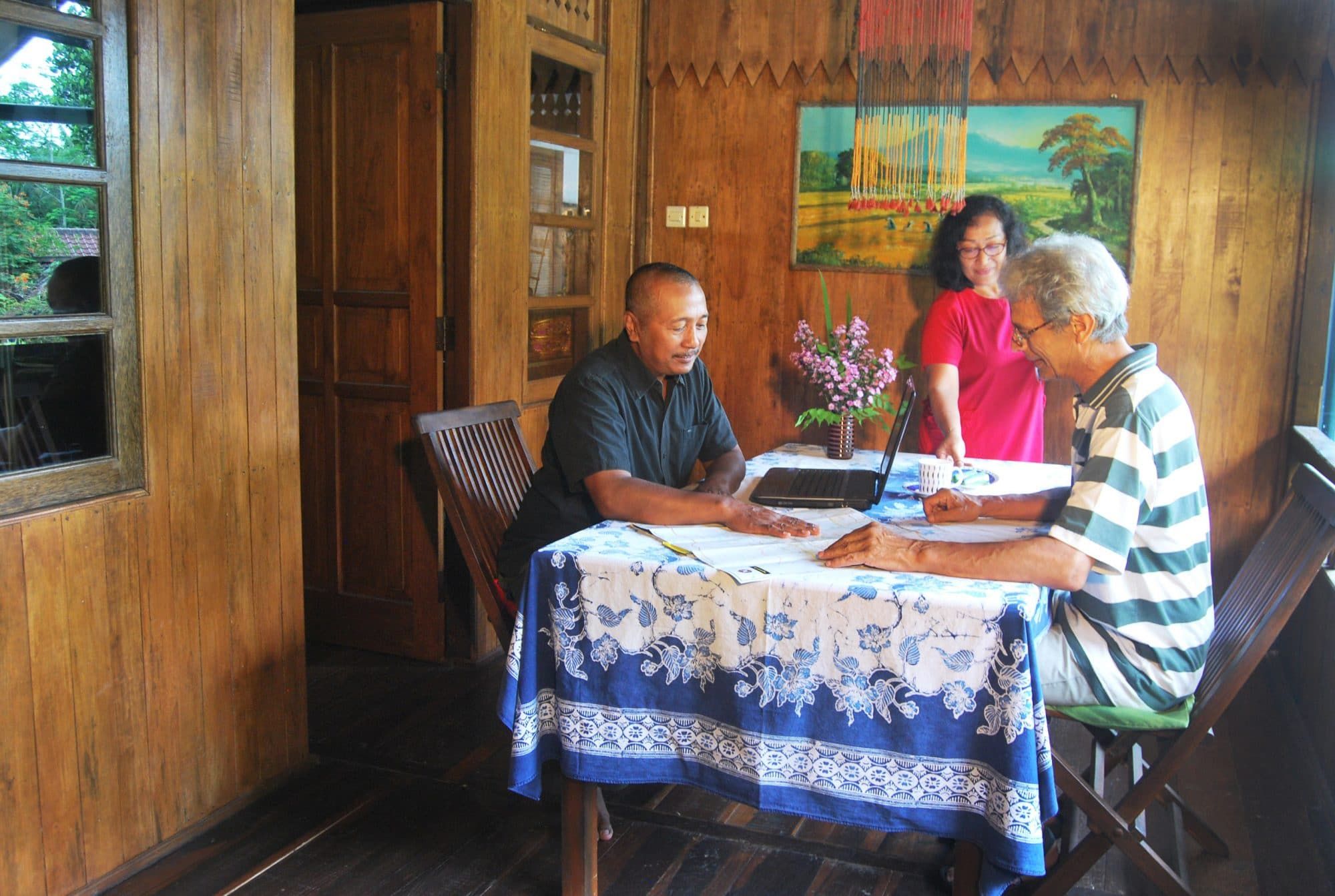 Villa Tanen staff helping guests plan their day at the table inside the wooden villa