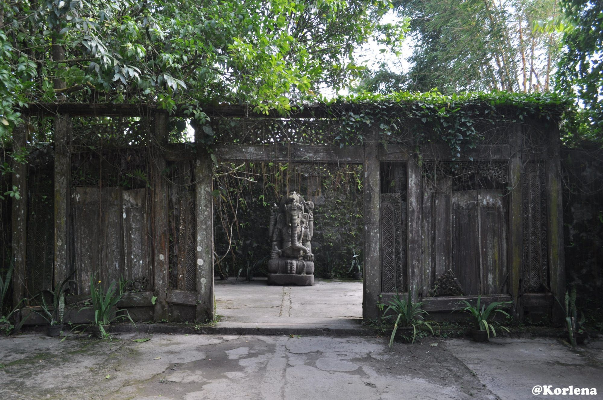 The entrance gate of Museum Ullen Sentalu in Kaliurang — carved wooden gate with Ganesha statue framed by tropical green