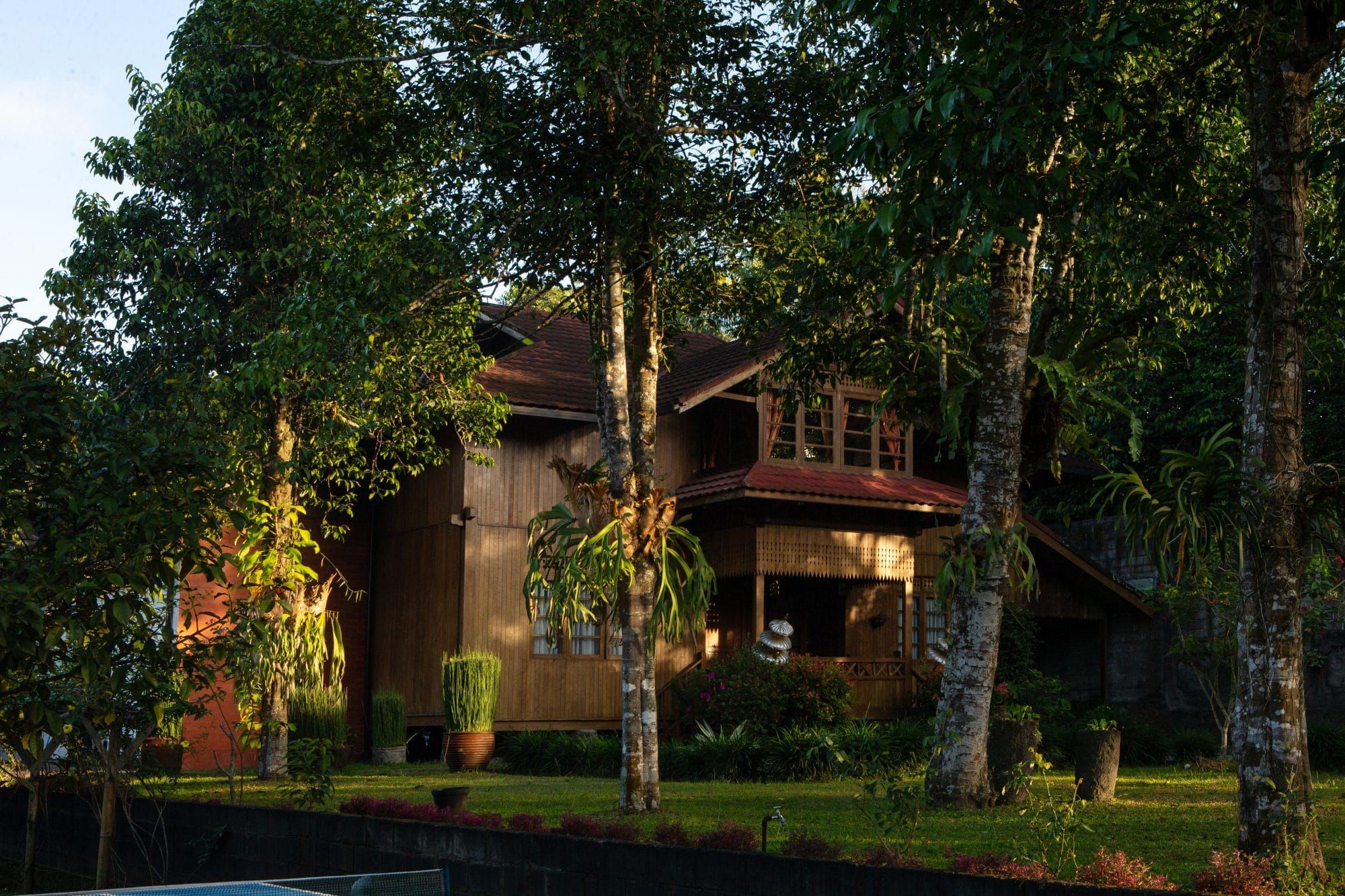 Villa Tanen in the hills above Yogyakarta in warm evening light — the traditional wooden house set in its tropical garden, about 21 km north of the city