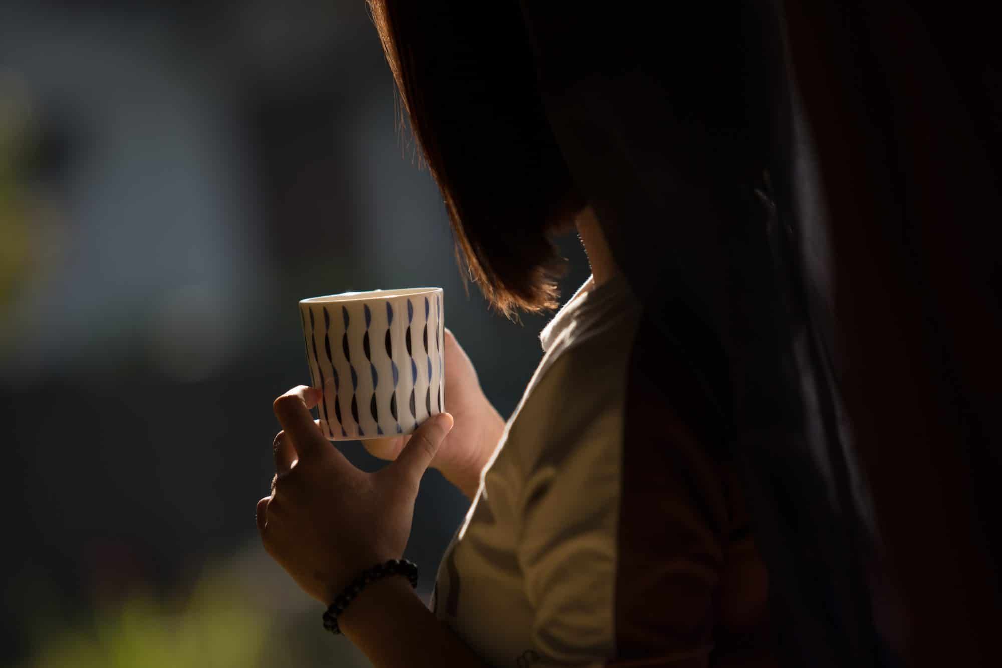 A member of Villa Tanen's staff holding a cup of tea — personal hospitality is the hallmark of the house
