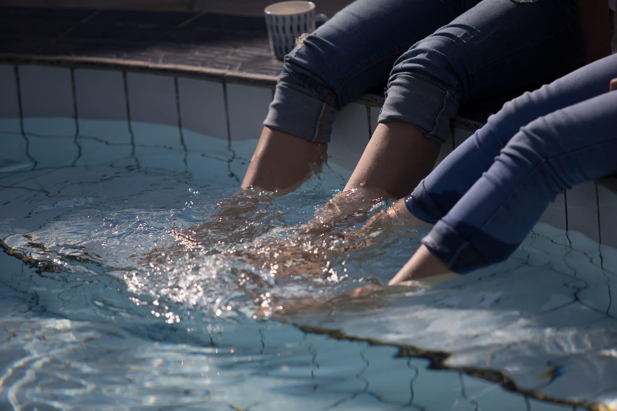 Guests dipping their feet in the private pool at Villa Tanen, coffee within reach — an unhurried morning moment in the garden