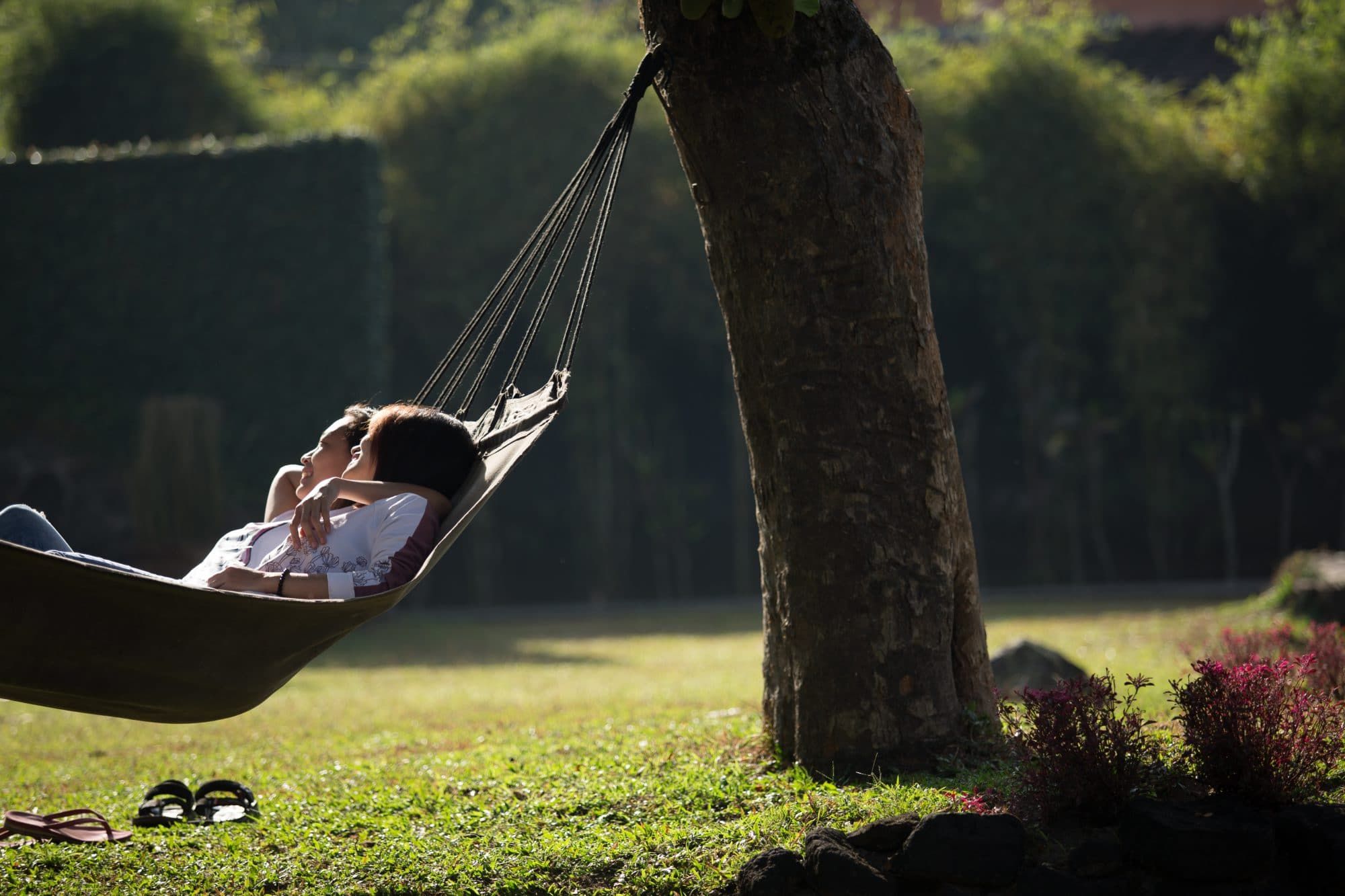 Two people lying in a hammock in the walled garden of Villa Tanen in morning light