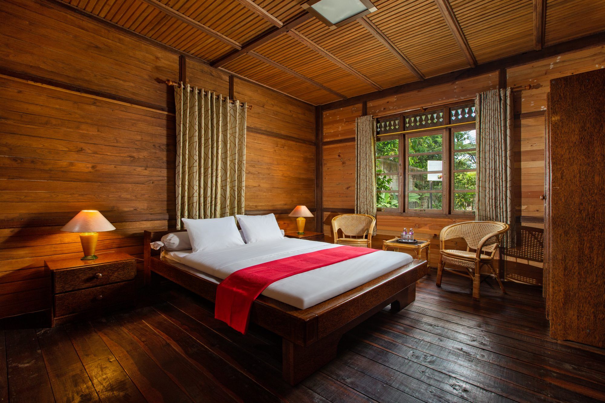 Double room with wooden panelling and red accent throw, garden visible through the window