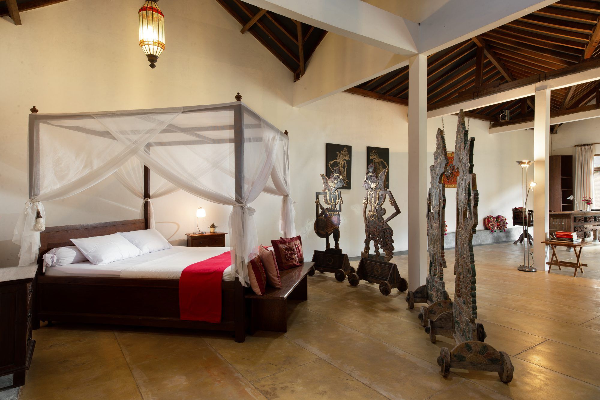 Bedroom in Rumah Pojok studio — four-poster bed, lantern and atmospheric wooden details